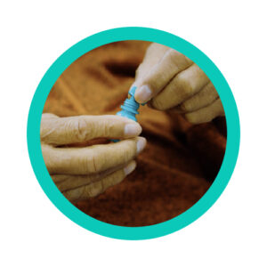 a patient carefully placing the cap back on an eye drop medicine bottle